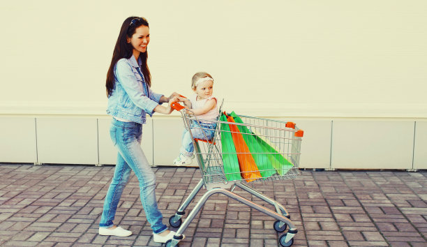 幸福微笑的母子带着购物袋和手推车在城市中行走图片下载