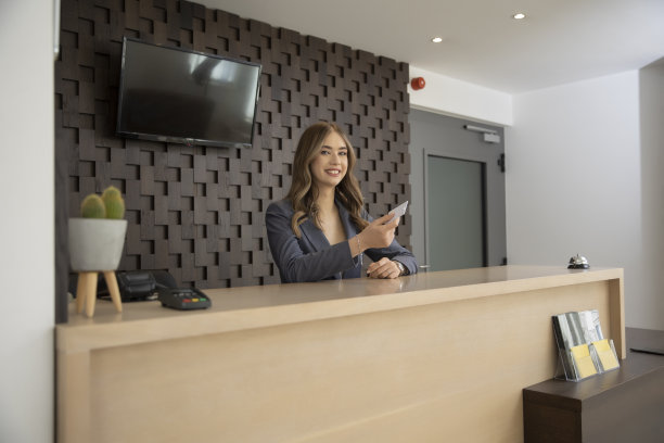 微笑的酒店接待员拿着钥匙卡在酒店前台图片下载