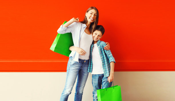 幸福微笑的母子带着购物袋一起走在城市里图片下载