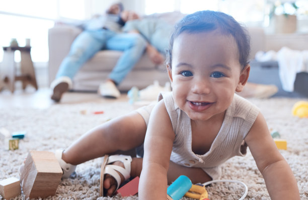 这张照片拍摄的是一个小女孩在地板上玩耍，而她的父母在后面打盹图片下载