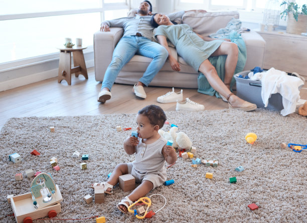 这张照片拍摄的是一个小女孩在地板上玩耍，而她的父母在后面打盹图片下载