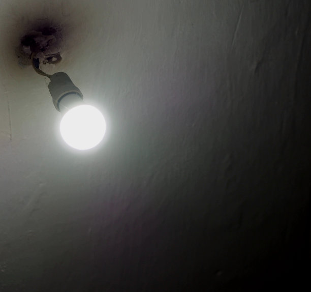 特写的一个室内白色灯泡在一个墨盒与电线从天花板上白色背景与一个大空间。图片下载