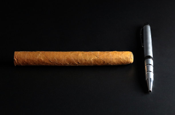 黑色背景上的古巴雪茄和钢笔图片下载