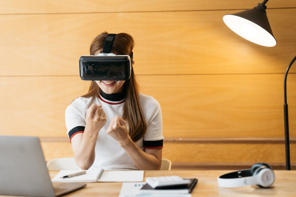 一个女人戴着虚拟现实眼镜站在办公室里。虚拟现实眼镜。360度。虚拟现实耳机。虚拟现实的游戏。佩戴虚拟现实眼镜。智能手机与虚拟现实。虚拟现实的视频。图片下载