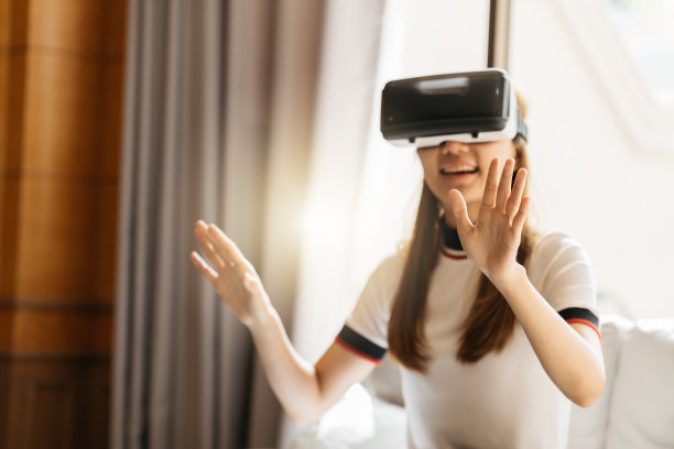 戴VR眼镜的女人。自信的年轻女性戴着虚拟现实耳机，坐在办公室的工作地点指着天空图片下载