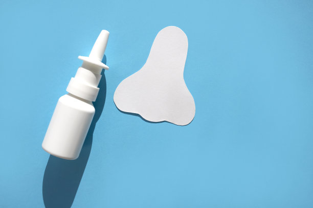 在蓝色背景上画一个鼻子和一罐喷雾的剪影。概念对抗过敏性鼻塞。图片下载