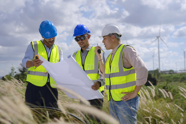 在电力工地的蓝领工人与风车图片下载