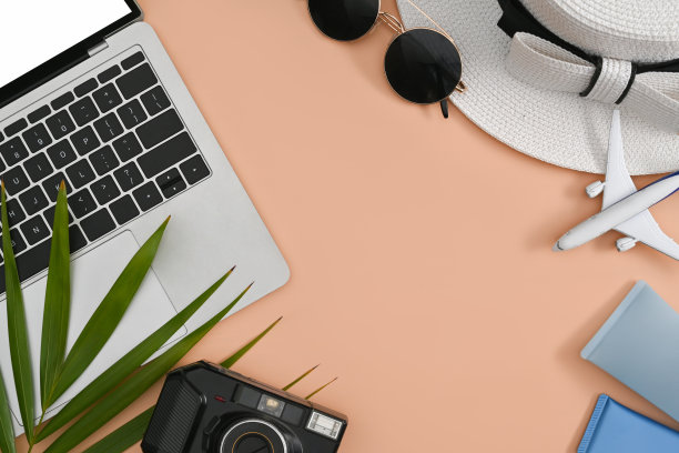 笔记本电脑，复古相机，太阳镜，防晒霜瓶和帽子在米色的背景。旅游，暑假和假期的概念。图片下载