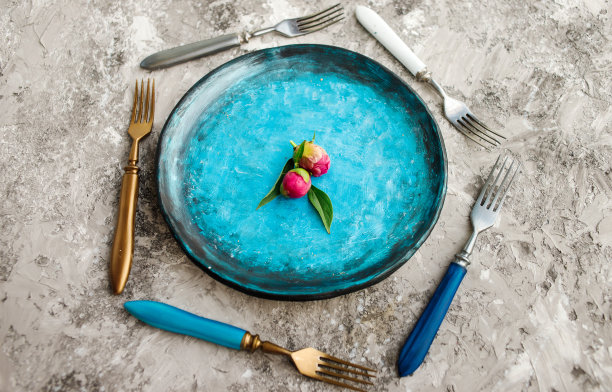 彩色的厨房盘子与叉子在灰色的背景。图片下载