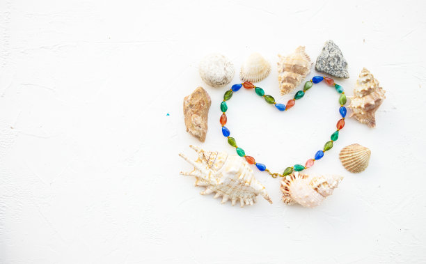 一套贝壳，珍珠和石头的形式心脏在白色的背景上。铭文。明信片。图片下载