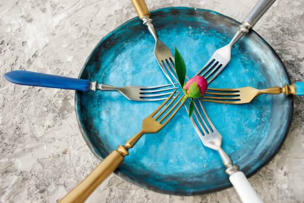 彩色的厨房盘子与叉子在灰色的背景。图片下载
