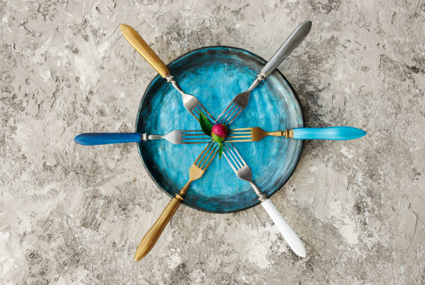 彩色的厨房盘子与叉子在灰色的背景。图片下载