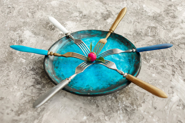 彩色的厨房盘子与叉子在灰色的背景。图片下载