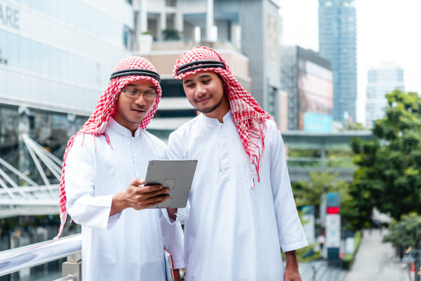 阿拉伯团队拿着数字平板电脑，讨论现代穆斯林阿联酋城市的数字营销图片下载