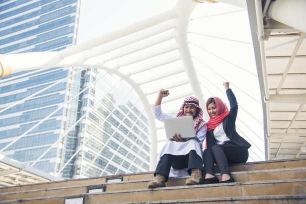 阿拉伯团队拿着数字平板电脑，讨论现代穆斯林阿联酋城市的数字营销图片下载