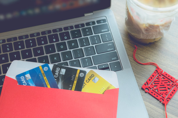 红包里的信用卡在笔记本电脑上，上面写着中文的祝福，是一个春天，咖啡隔离在木制背景的办公桌上，作为春节奖金图片下载