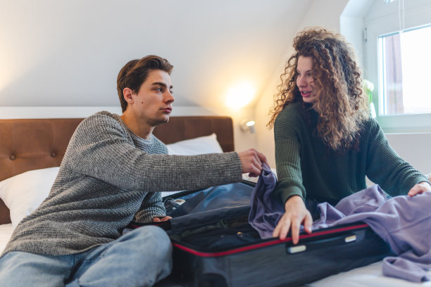 一对漂亮的年轻夫妇正在卧室里收拾行李图片下载