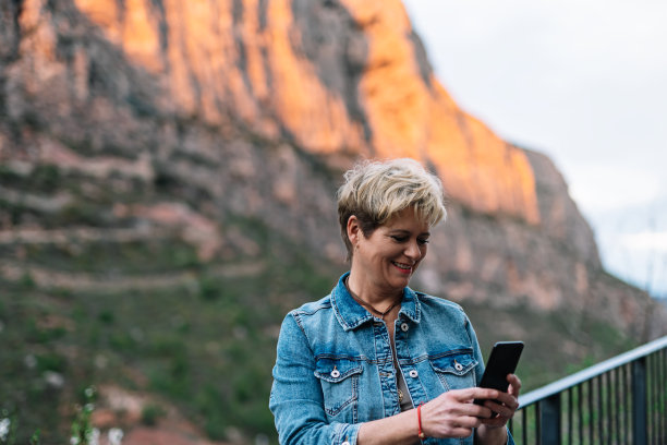 成年金发短发女人，在假日与她的手机分享照片，她的家人。图片下载