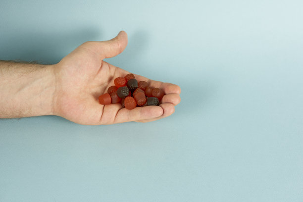 一个男人的手拿着一把给孩子们吃的维生素，背景是蓝色的。健康的概念与文本的空间。图片下载