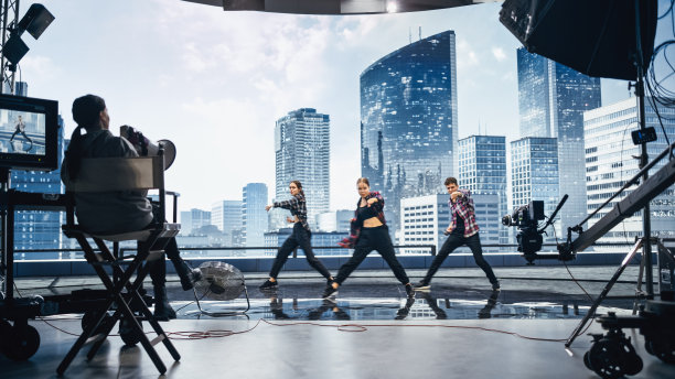 音乐剪辑工作室:拍摄嘻哈视频舞蹈场景，三名专业舞者在大Led屏幕的舞台上表演，背景是现代城市。导演和摄影师在后台。图片下载