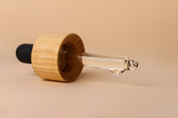 用透明质酸或天然油剂量的移液管的特写照片。滴落在它的末端。美丽的中性色调，文字的复制空间。图片下载