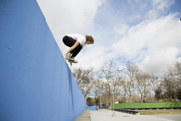 一头金色卷发和一件白色t恤的少年在墙上跳来跳去图片下载