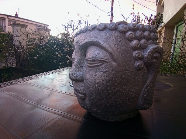一张放在户外桌子上的佛像头像的照片图片下载