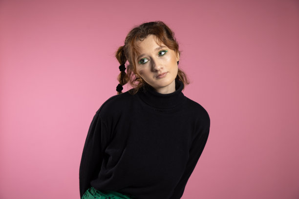 友好的年轻女子，面带活泼的微笑，情绪激动。年轻的红发女孩在粉红色的背景图片下载