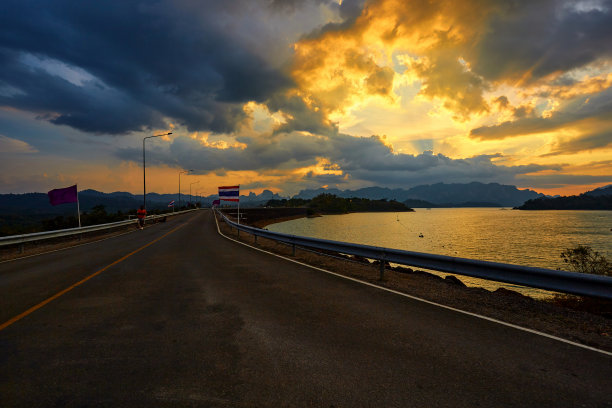 夕阳越过大坝，人们在柏油路上奔跑图片下载