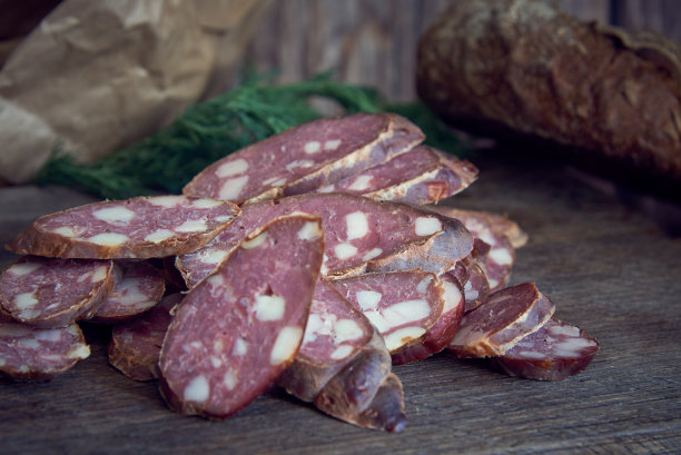 烟熏香肠，切成片，躺在木板上。图片下载