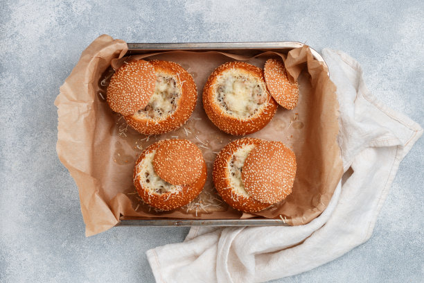 在烤盘上放上切好的芝麻面包。面包卷配奶酪、蘑菇、鸡肉和白酱。美味的自制早餐、午餐或晚餐。选择性聚焦，俯视图图片下载