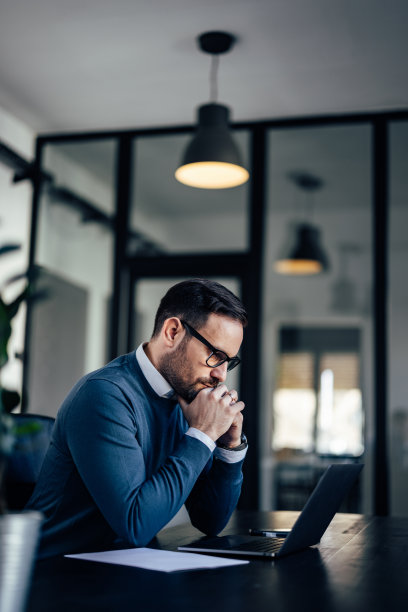 自信的商人，看起来很专注，在网上工作，等待图片下载