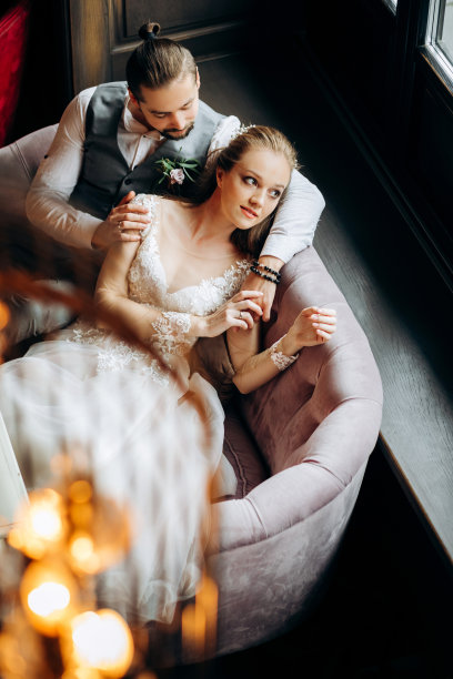 一对神奇的年轻夫妇坐在沙发上。前视图。图片下载