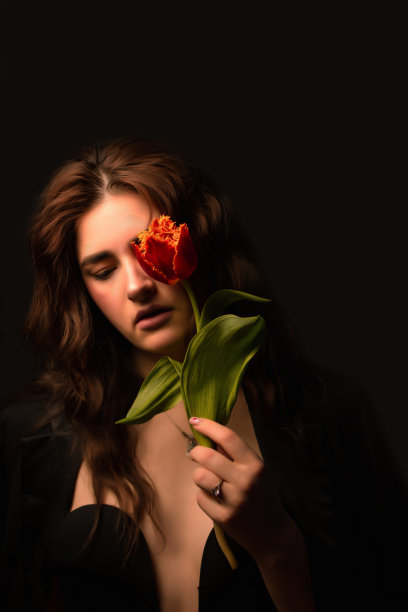 一名戴着墨镜的年轻女子的工作室肖像，背景是黑色的，手里拿着一束红色的郁金香。国际妇女节。情人节图片下载