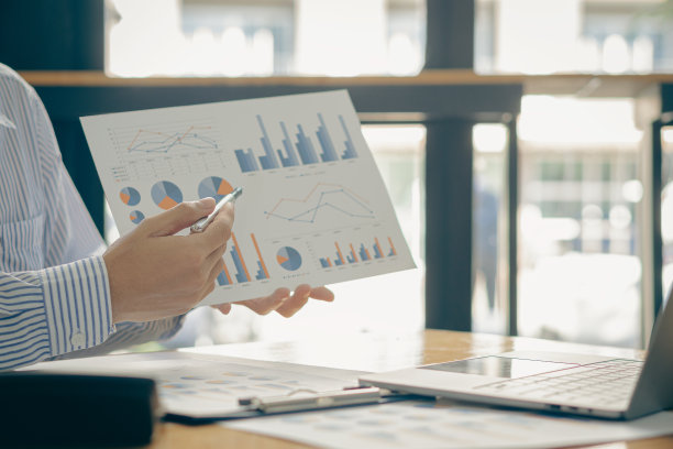 会计人员处理商业报告中所计算的数据表。办公室里有台笔记本电脑图片下载