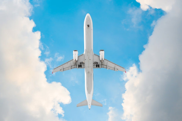 在美丽的云彩和蓝天的背景下，飞机在头顶上飞行。图片下载