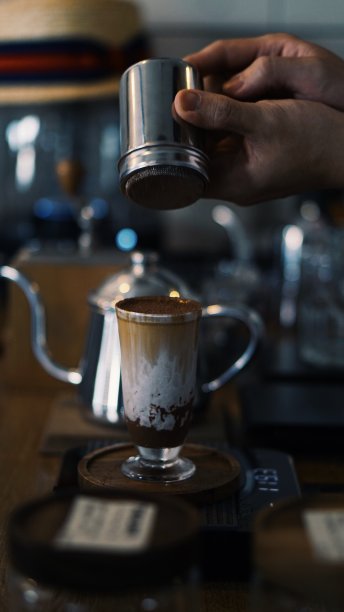 咖啡师为顾客倒巧克力粉在咖啡饮料上-库存照片图片下载