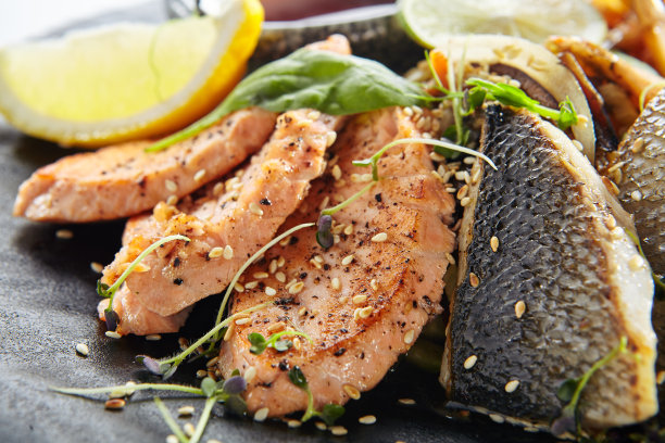 铁板烧海鲜-烧烤海鲜与酱油和蔬菜。日式铁板烧三文鱼排、虾、扇贝及鱼片配柠檬及蔬菜沙拉。图片下载