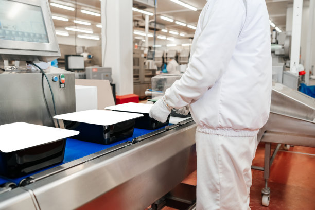 生产线用于生产肉制品半成品。食品工业中的肉类加工。在传送带上把肉片装在盒子里。现代家禽加工厂。图片下载