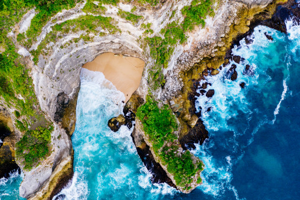 蓝色的海洋和热带植物覆盖的悬崖。从上面俯瞰巴厘岛海岸。空中无人机拍摄。图片下载