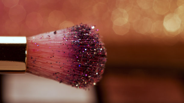 化妆刷和亮片在闪亮的粉红色背景上闪闪发光图片下载