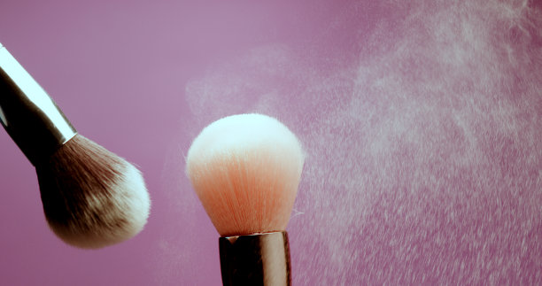 在紫色的背景上化妆笔刷。工作室近距离拍摄的粉末云图片下载