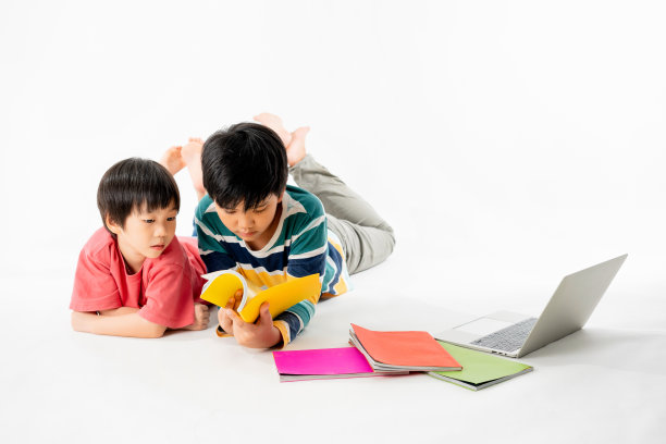 快乐亚洲男孩的肖像，兄弟在地板上笔记本电脑和书本孤立的白色背景，教育和学习的技术概念图片下载