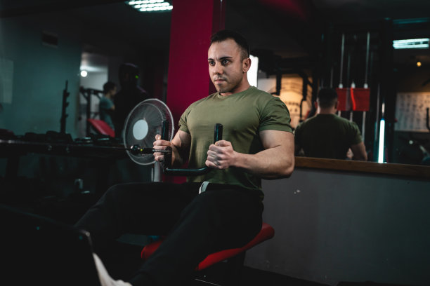 一名男子年轻的成年白人男性健美运动员训练回来在健身房里的机器上穿着衬衫暗照片真人复制空间侧视图图片下载