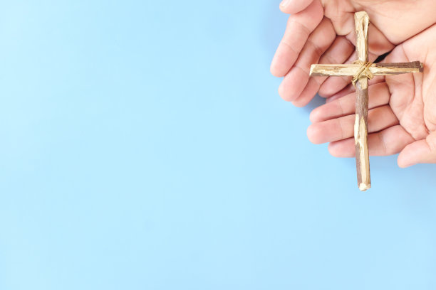 手握木制十字架与蓝色背景复制空间的俯视图。天主教、基督教、感恩、天主教和基督教的信仰观念。图片下载