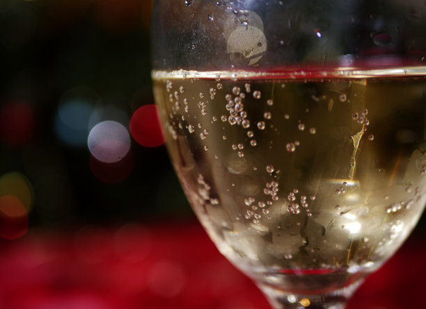 圣诞散景灯光背景下的一杯白葡萄酒图片下载