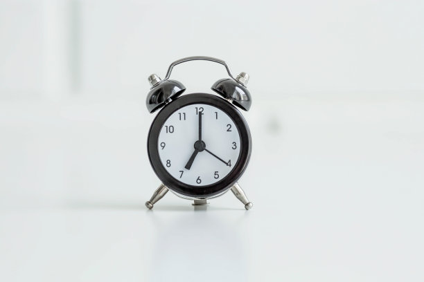 黑色复古闹钟在白色砖墙背景。早上好时间的概念。图片下载