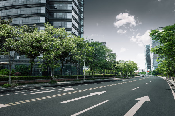 在晴朗的天空下，柏油路前矗立着现代化的城市建筑图片下载