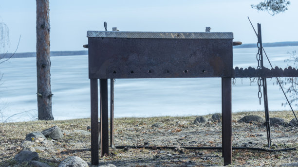 在一个阳光明媚的春日，在冰冻的湖边烧烤。一个肉焙烧炉。野餐和休闲的概念。烧烤用的大火盆。图片下载