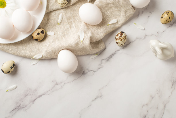 俯视图照片的盘子与雏菊和三个鸡蛋的纹理布与几个鸡蛋和陶瓷兔子在孤立的大理石空背景图片下载